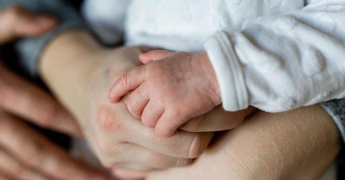 Vortrag: Wenn der Körper spricht Hände eines Eltern und eines Babys halten sich fest